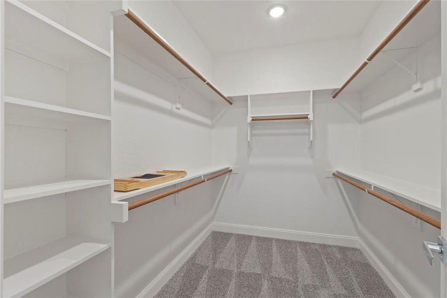 Walk-in closet featuring built-in shelving, white walls, wood-finish hanging rods, and recessed lighting Walk-in closet featuring built-in shelving, white walls, wood-finish hanging rods, and recessed lighting