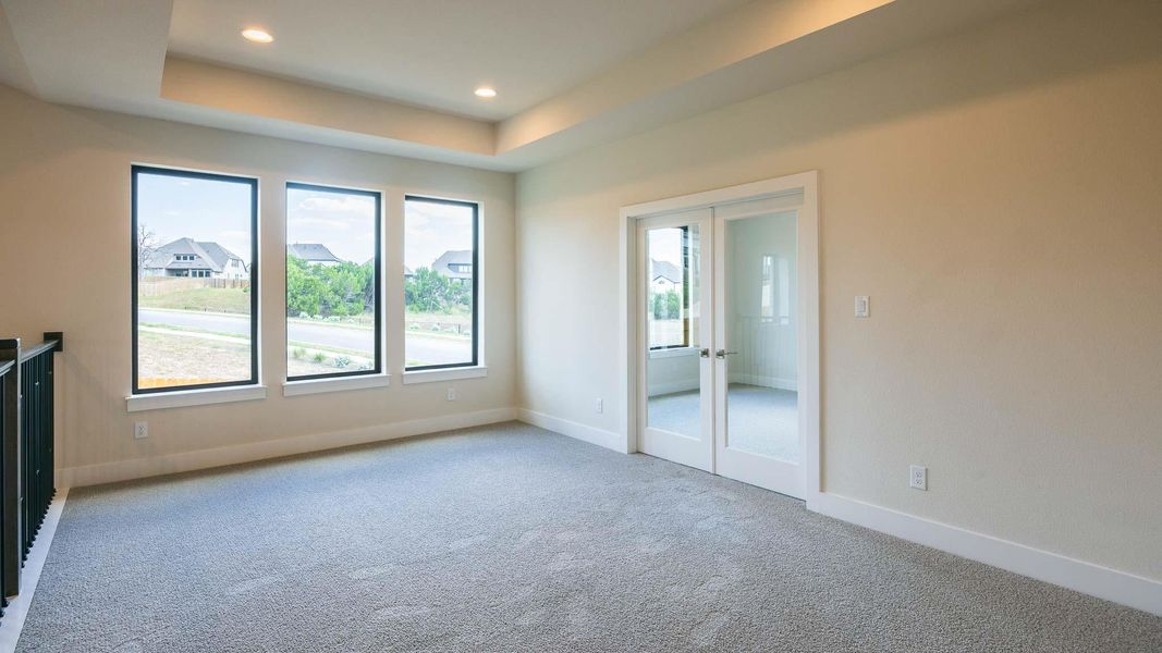 Unfurnished bedroom with light carpet, french doors, a raised ceiling, and recessed lighting Unfurnished bedroom with light carpet, french doors, a raised ceiling, and recessed lighting