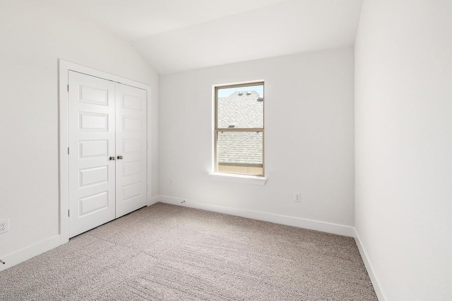 Carpeted spare room with baseboards and vaulted ceiling Carpeted spare room with baseboards and vaulted ceiling