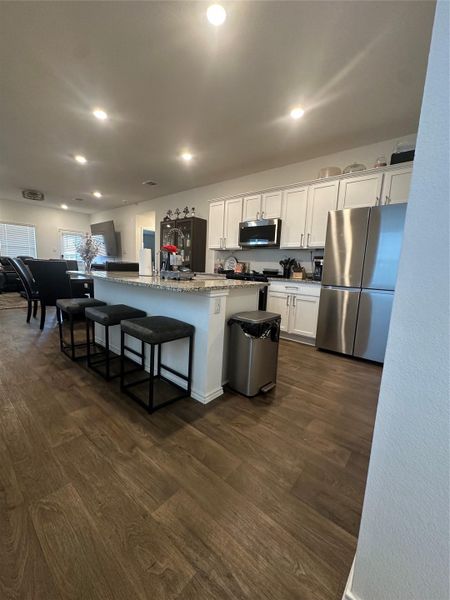 Kitchen with stainless steel appliances, white cabinetry, an island with sink, recessed lighting, and dark wood-style flooring