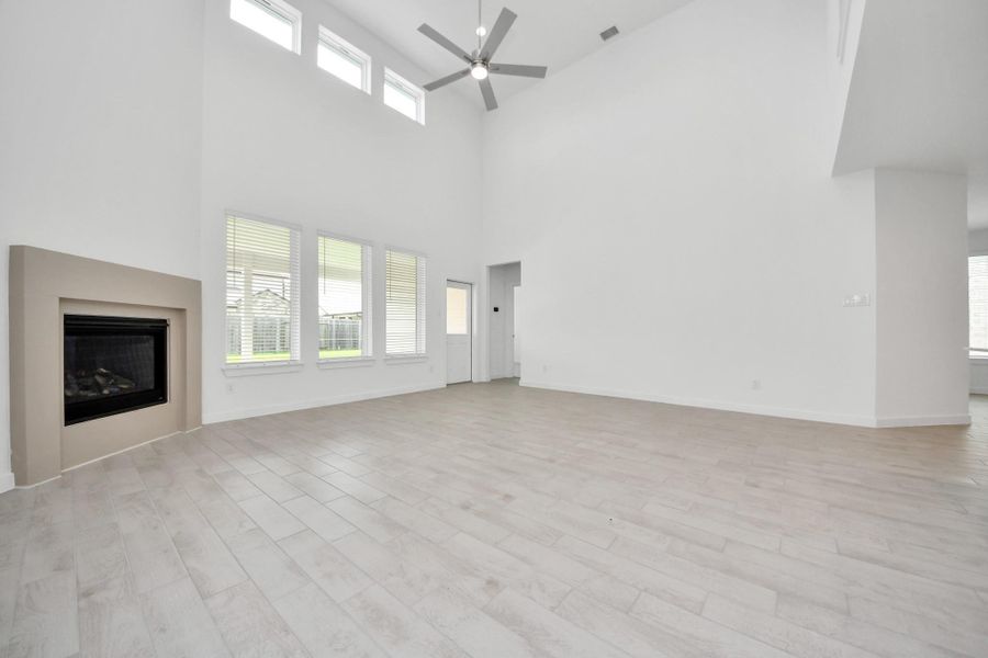 Welcome family and guests to your charming living room! With its high ceilings, recessed lighting, ceiling fan, custom paint, beautiful flooring, and large windows that let in abundant natural light, this room is perfect for gatherings.  Sample photo of completed home with similar floor plan. Actual colors and selections may vary.