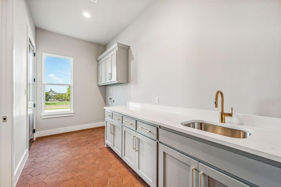 Laundry area featuring cabinets, light tile patterned floors, washer hookup, and sink