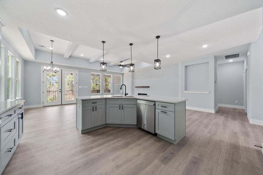 Contemporary kitchen and living area featuring light wood-finish flooring