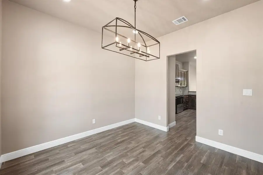 Dining room featuring chandelier facing the adjacent kitchen area