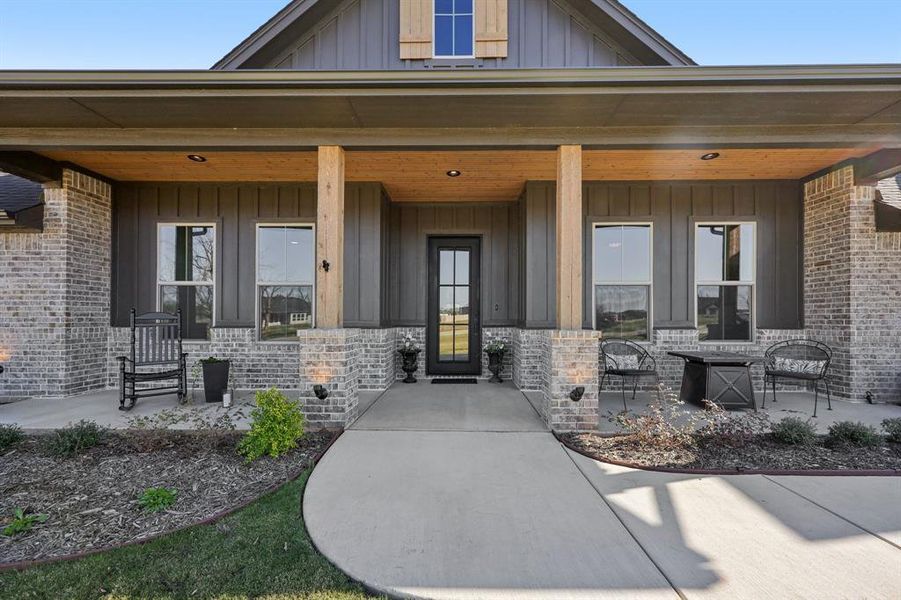 Property entrance featuring covered porch, board and batten siding, and brick siding Property entrance featuring covered porch, board and batten siding, and brick siding