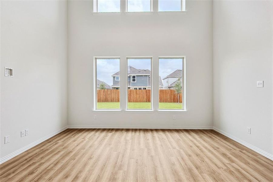 Empty room featuring a healthy amount of sunlight, a high ceiling, and light hardwood / wood-style flooring