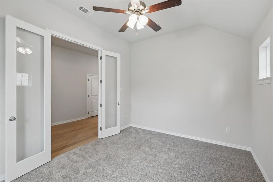 Empty room featuring carpet, lofted ceiling, a ceiling fan, and french doors Empty room featuring carpet, lofted ceiling, a ceiling fan, and french doors