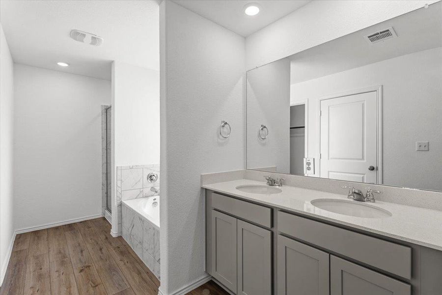 Full bathroom with double vanity, a stall shower, dark wood-style floors, a bath, and recessed lighting