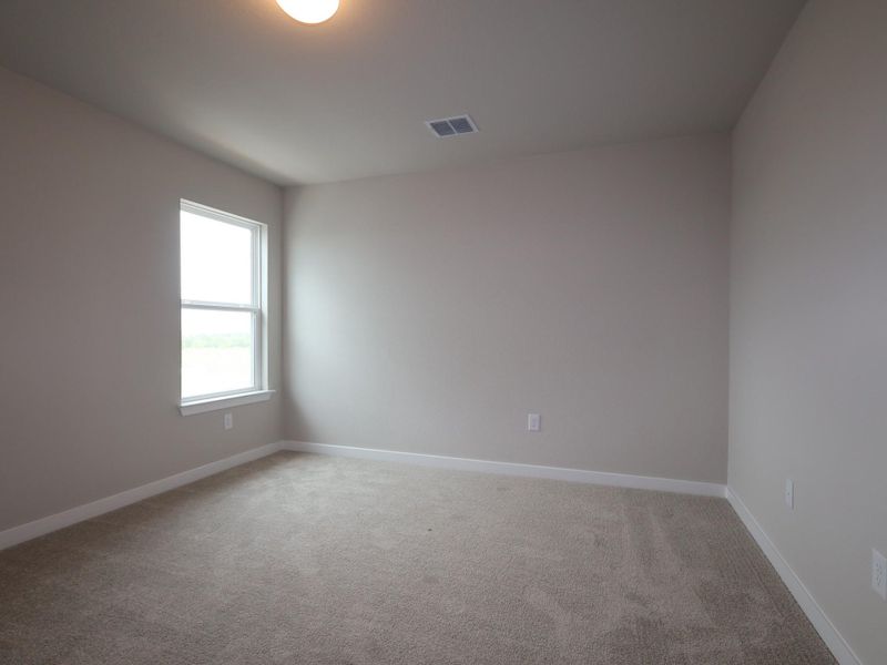 A well-lit room offers ample natural light and plush carpeting, creating a comfortable ambiance.