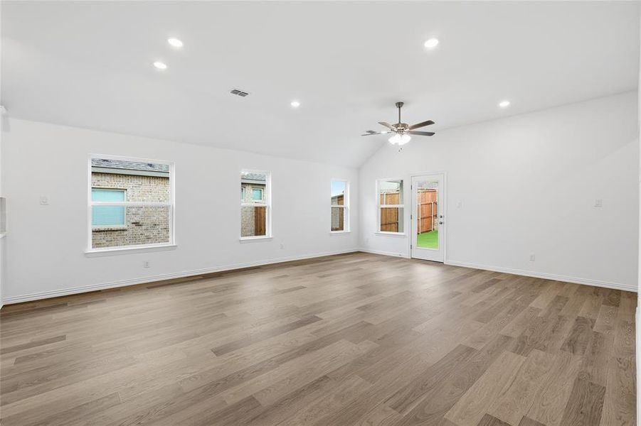 Spacious living area featuring wood-finish flooring, vaulted ceiling, recessed lighting, and a ceiling fan