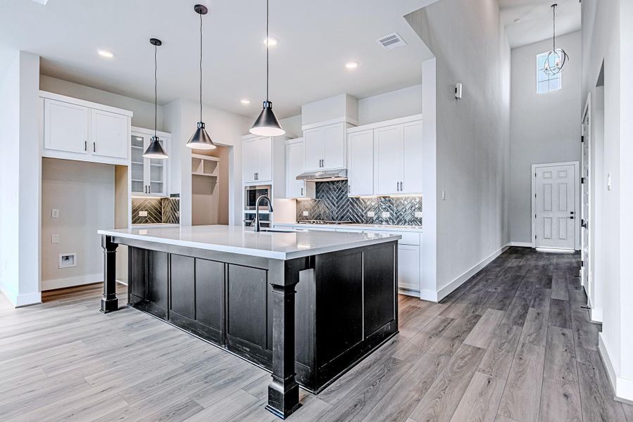 Open-concept kitchen with a large island, pendant lighting, and seamless flow into the living area.