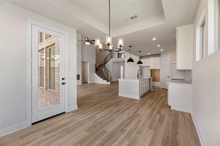 Kitchen featuring a chandelier, open floor plan, hanging light fixtures, a kitchen island with sink, and white cabinets