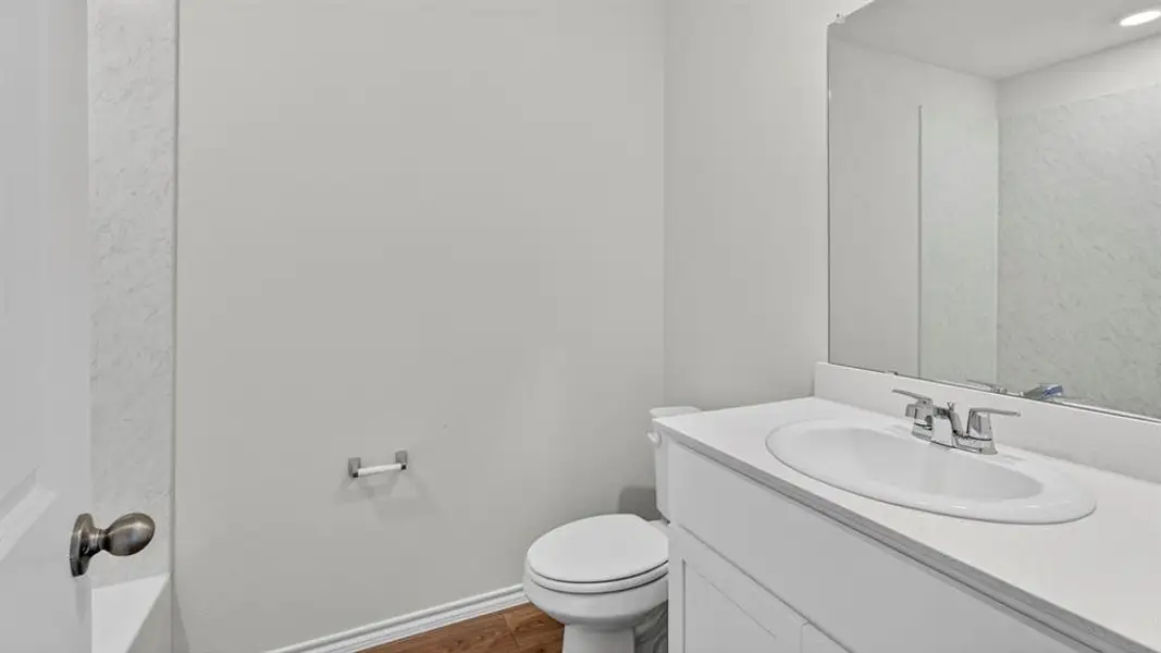 Bathroom vanity featuring an integrated sink with chrome faucet, a rectangular mirror, and white cabinetry Bathroom vanity featuring an integrated sink with chrome faucet, a rectangular mirror, and white cabinetry