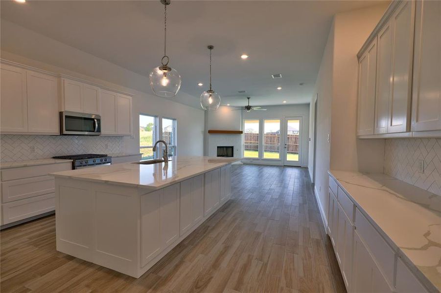 Kitchen with stainless steel appliances, a fireplace, healthy amount of natural light, open floor plan, and recessed lighting Kitchen with stainless steel appliances, a fireplace, healthy amount of natural light, open floor plan, and recessed lighting