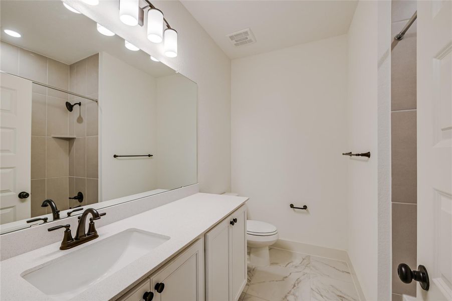 Full bath featuring vanity, a shower, and light marble finish floors