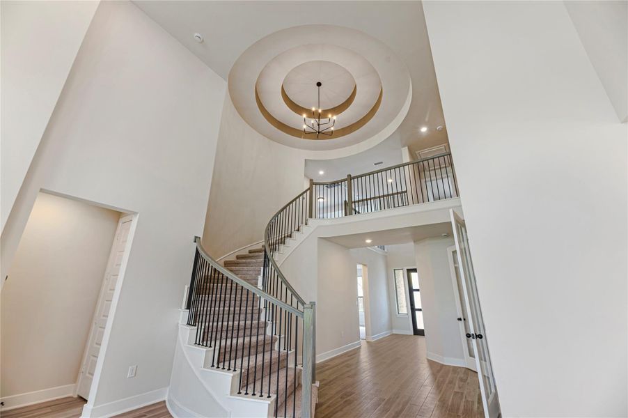 Staircase with wood finished floors, a chandelier, a high ceiling, and recessed lighting