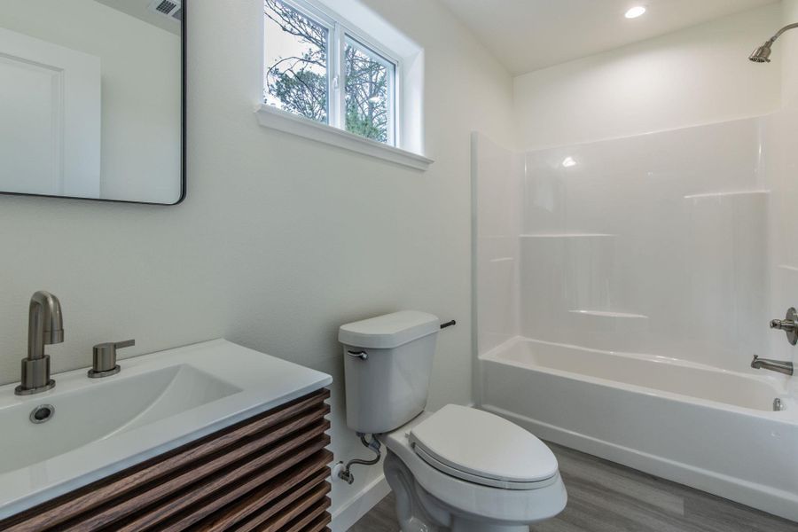 Bathroom with a wood-finish vanity, integrated sink, and brushed nickel faucet Bathroom with a wood-finish vanity, integrated sink, and brushed nickel faucet