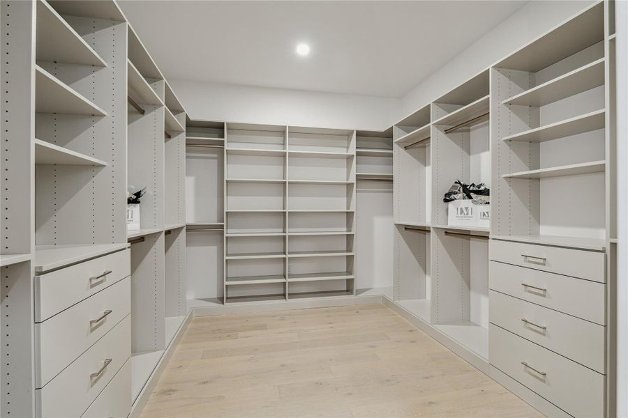 Primary walk-in closet thoughtfully designed with custom built-out shelving and storage. Primary walk-in closet thoughtfully designed with custom built-out shelving and storage.
