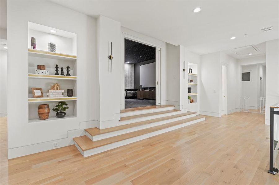 Hallway with built in shelves, light wood-style floors, and recessed lighting Hallway with built in shelves, light wood-style floors, and recessed lighting