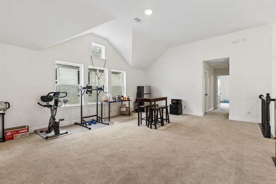 Spacious bonus room featuring vaulted ceilings, recessed lighting, neutral carpeting, and a window bank offering natural illumination