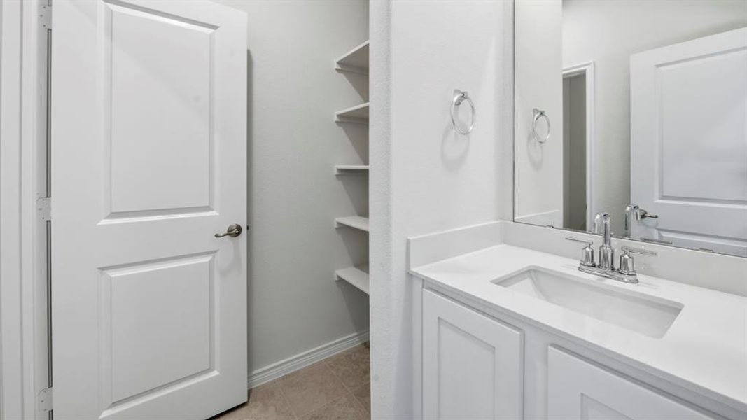 Bathroom with vanity, light tile patterned floors, and a closet Bathroom with vanity, light tile patterned floors, and a closet