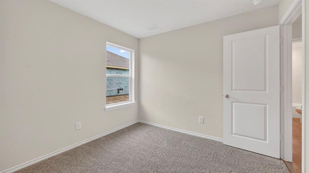 Neutral-toned room featuring light gray walls, gray carpet flooring, and a white two-panel door