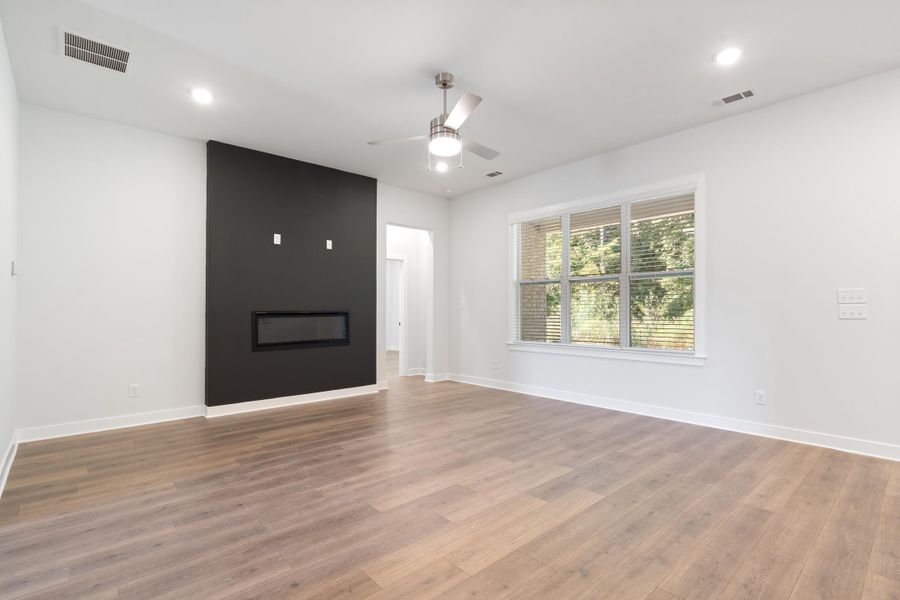 Contemporary living space featuring wood-finish flooring, a built-in linear fireplace, recessed lighting, and a ceiling fan
