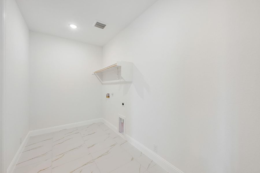 Empty laundry room with marble tile floor, wall shelf, and washer and dryer hookups Empty laundry room with marble tile floor, wall shelf, and washer and dryer hookups
