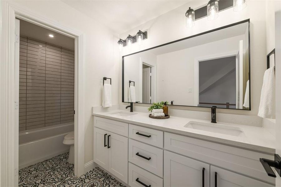 Full bath featuring double vanity, shower / bath combination, and light tile patterned floors Full bath featuring double vanity, shower / bath combination, and light tile patterned floors