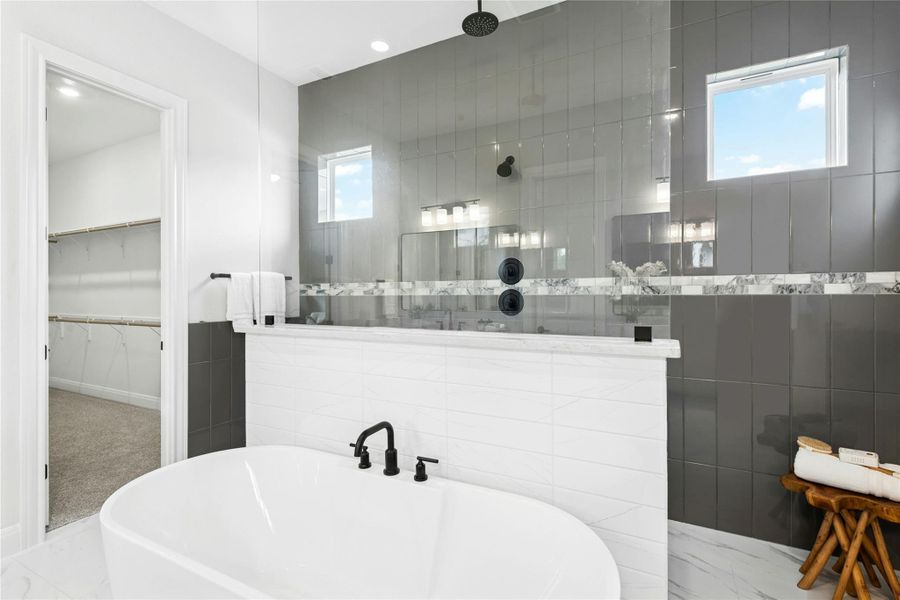 Full bathroom featuring a freestanding bath, a walk in closet, walk in shower, and tile walls Full bathroom featuring a freestanding bath, a walk in closet, walk in shower, and tile walls