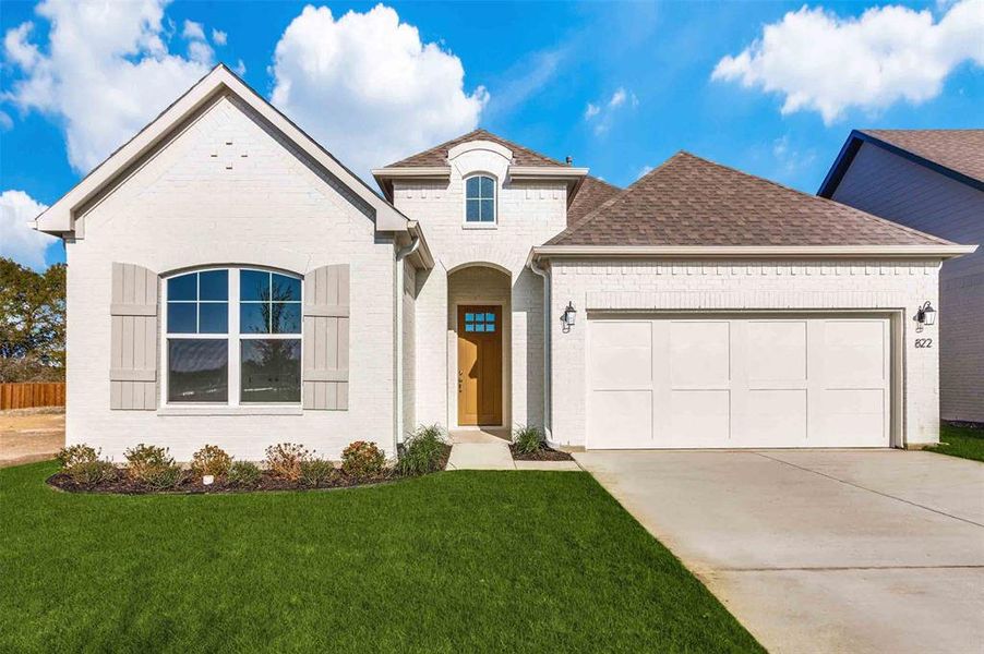 French country inspired facade with a front lawn and a garage