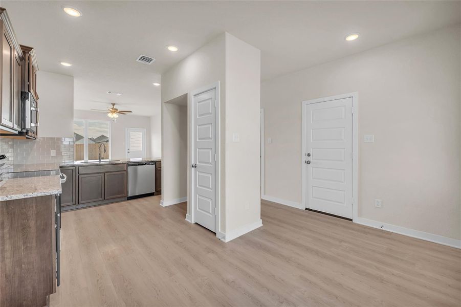 Kitchen featuring tasteful backsplash, light stone counters, appliances with stainless steel finishes, dark brown cabinets, and recessed lighting
