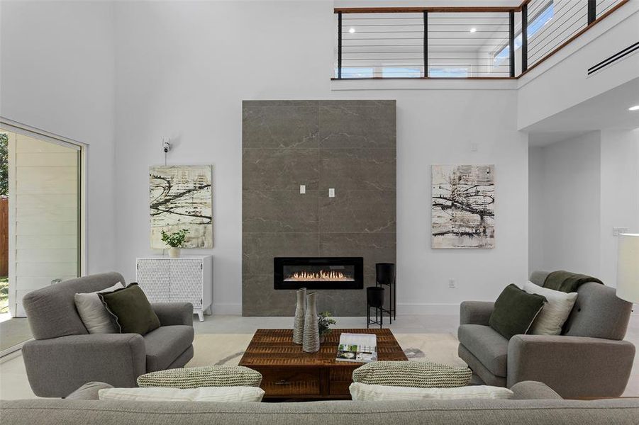 Tiled living room featuring a wealth of natural light, a tiled fireplace, and a towering ceiling