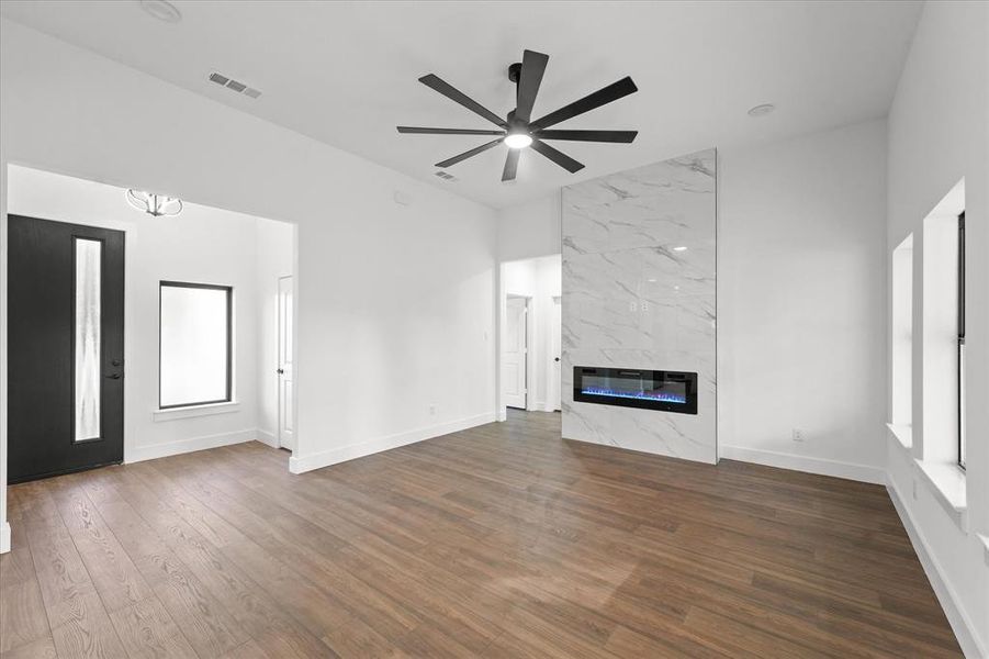 Unfurnished living room with a fireplace, ceiling fan with notable chandelier, dark hardwood / wood-style floors, and heating unit