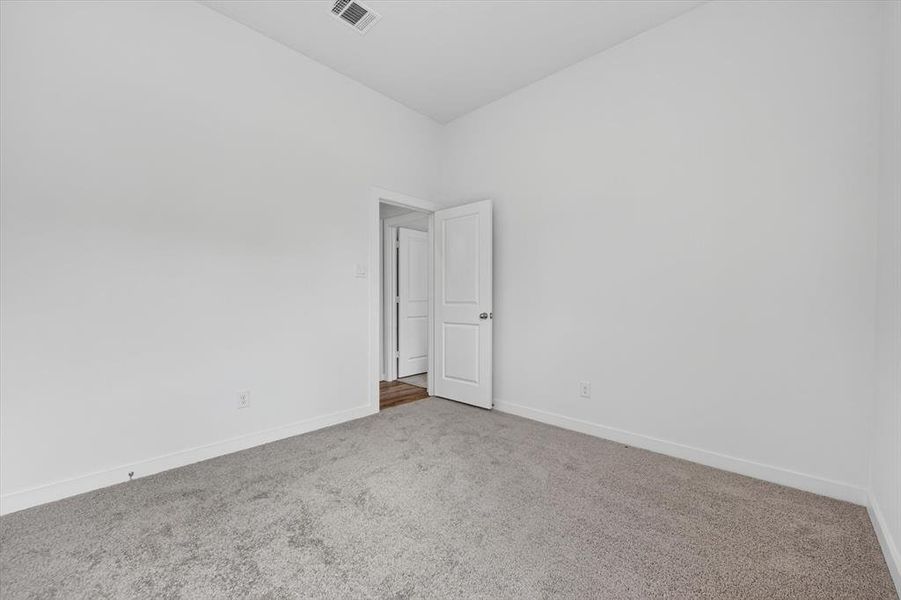 Room featuring light gray carpeting, white walls, white baseboards, and a white interior door with a silver handle
