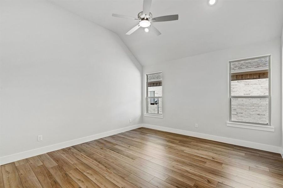 Spare room featuring ceiling fan, plenty of natural light, light wood-type flooring, and vaulted ceiling