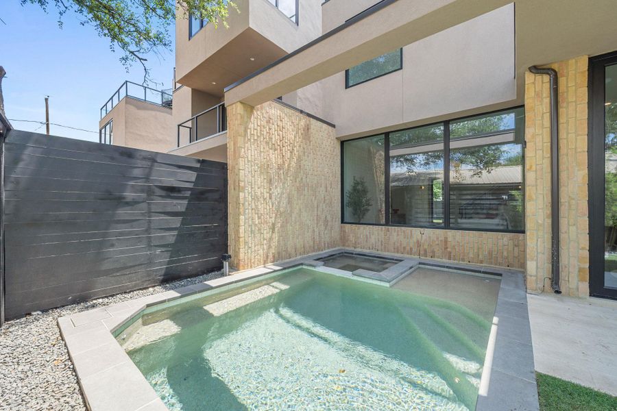 An inviting backyard oasis offers a sparkling pool with an integrated spa, perfect for relaxation.