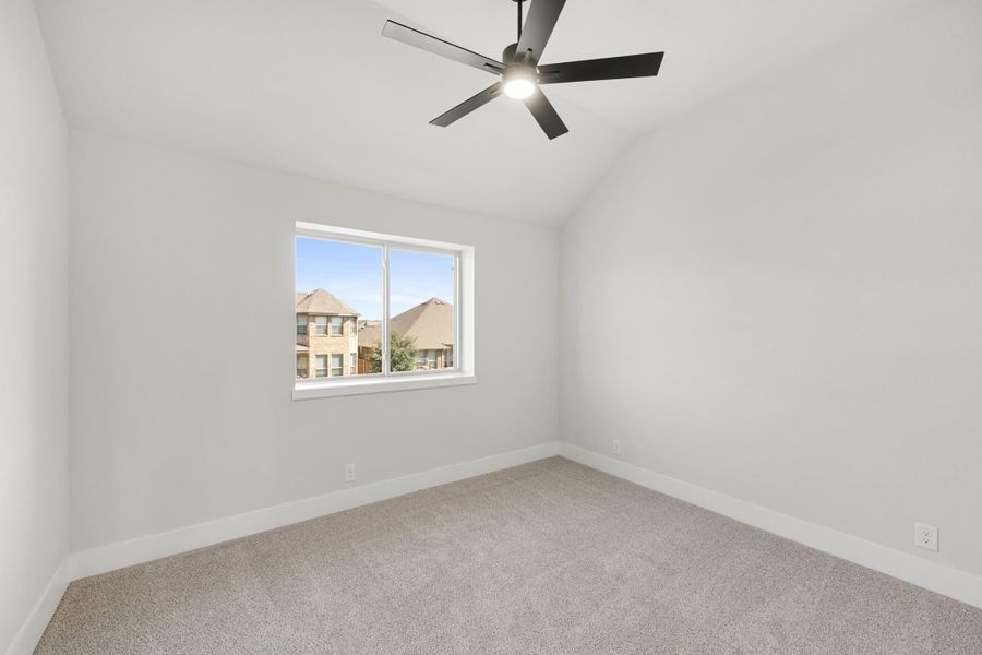 Empty bedroom with vaulted ceiling, black ceiling fan, carpet flooring, and single window