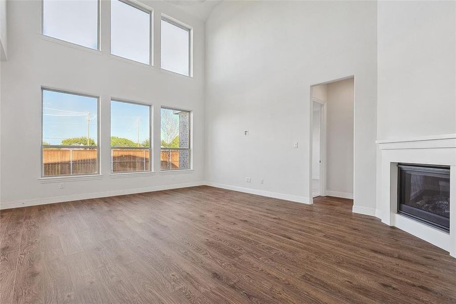 Unfurnished living room with hardwood / wood-style floors and a high ceiling