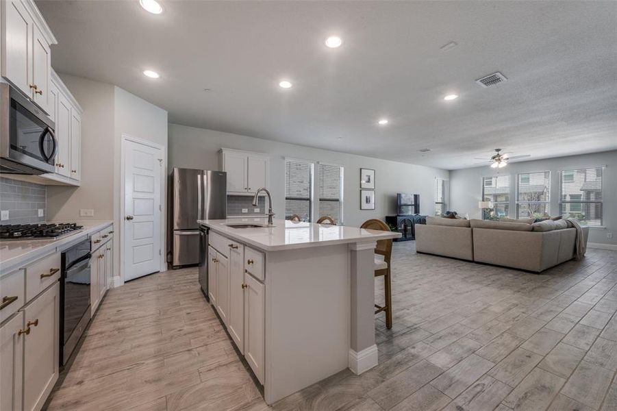 Oversized quartz island anchors the kitchen, complemented by abundant cabinetry, pantry storage, and modern finishes throughout.