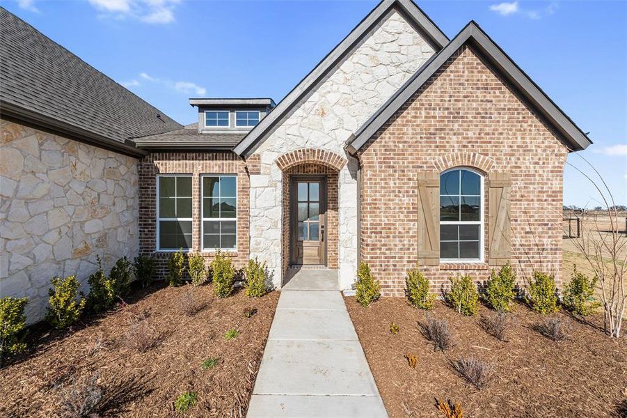 Property entrance featuring stone siding, brick siding, and a shingled roof