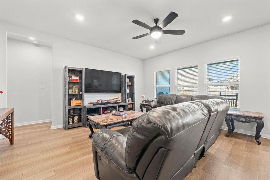 Living area with light wood-type flooring, recessed lighting, and a ceiling fan