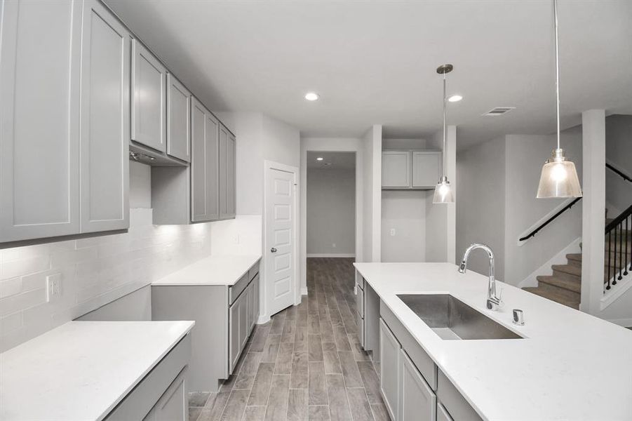 Culinary haven, featuring granite countertops, a tile backsplash, stainless steel appliances (to be installed), and 42” upper cabinets. Sample photo of completed home with similar floor plan. Actual colors and selections may vary.