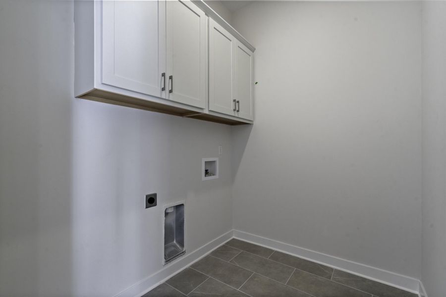 White shaker-style cabinetry with dark hardware, natural wood-finish trim, and plank-style tile flooring