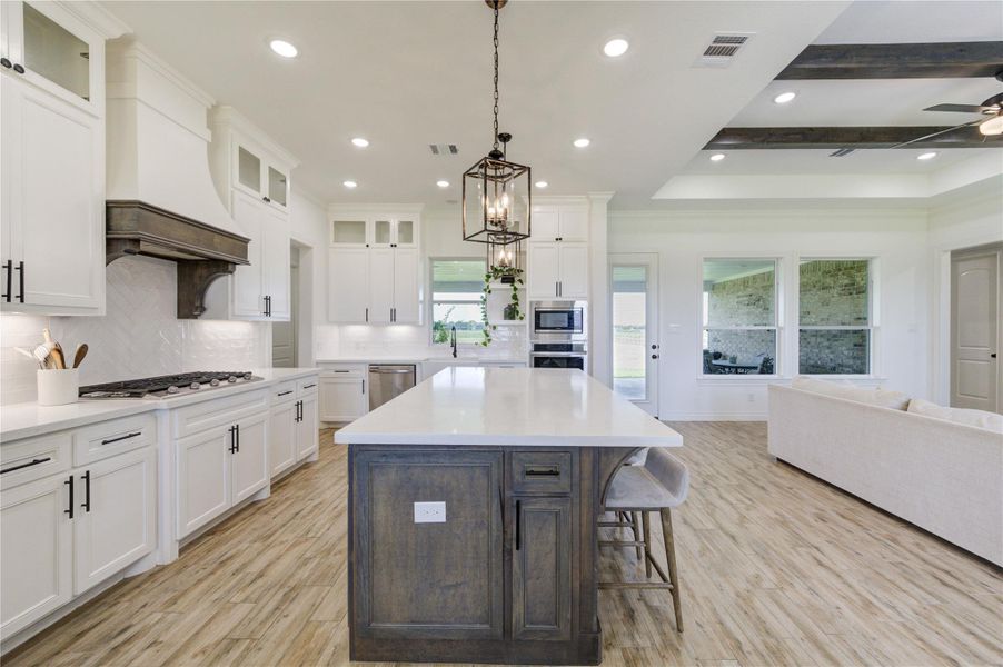 Chef’s kitchen with custom cabinetry, gas cooktop, and expansive quartz island.