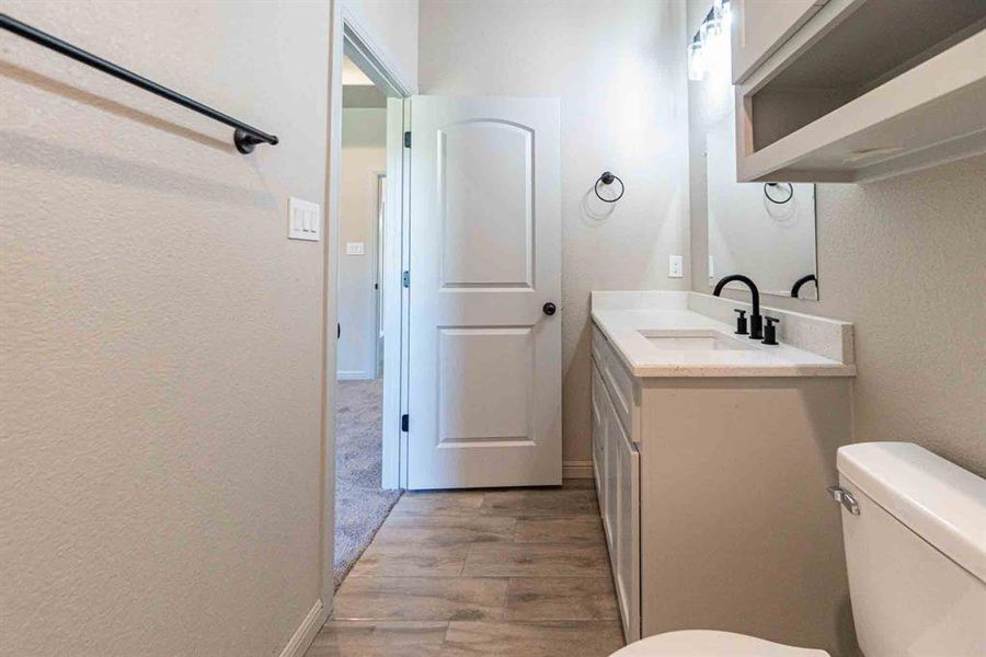 Bathroom with light wood-style flooring, vanity, and a textured wall