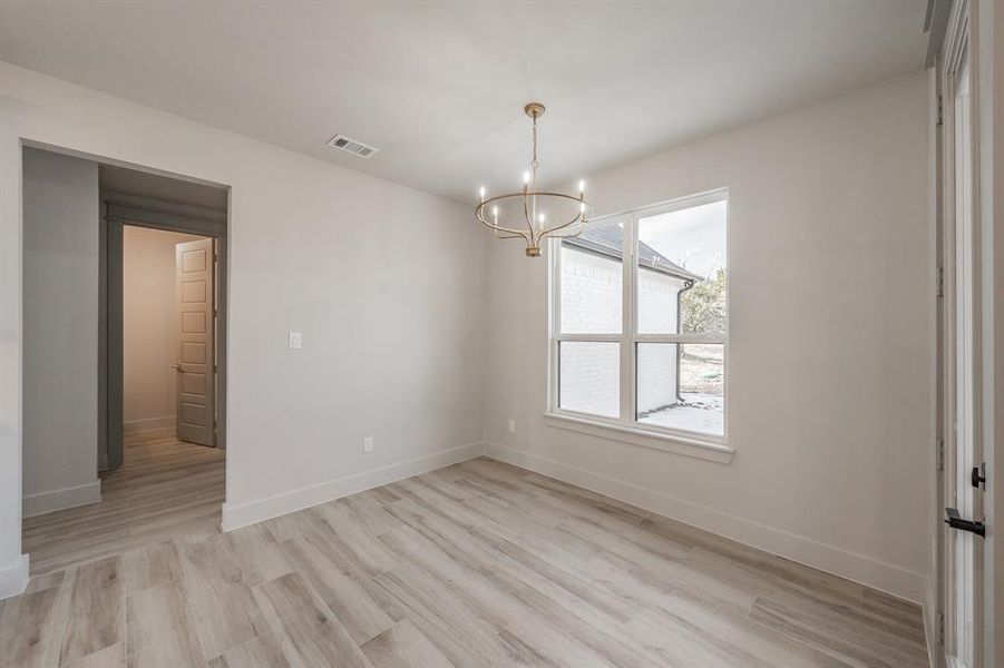 Spare room featuring light wood finished floors and a chandelier