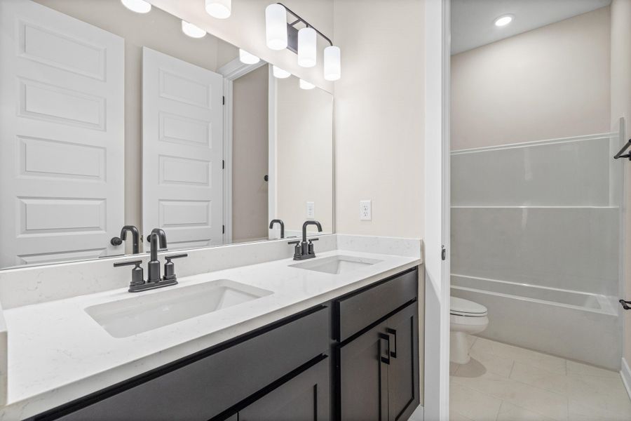 Double vanity featuring white rectangular undermount sinks, matte black faucets, and a light-colored countertop Double vanity featuring white rectangular undermount sinks, matte black faucets, and a light-colored countertop