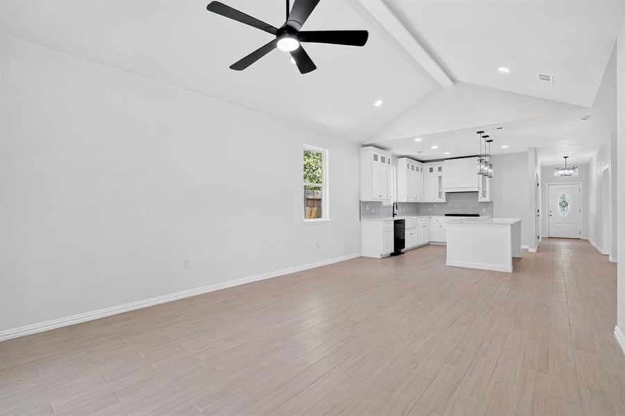 Open-concept living area featuring light wood-finish flooring and a vaulted ceiling with a ceiling fan