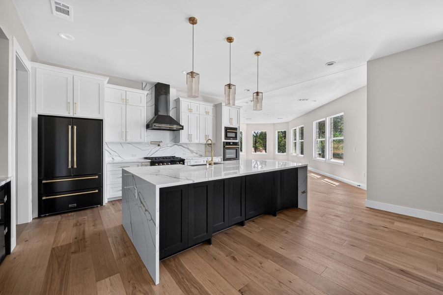 Gleaming hardwood floors and a spacious stone-topped island define this airy open-concept kitchen.